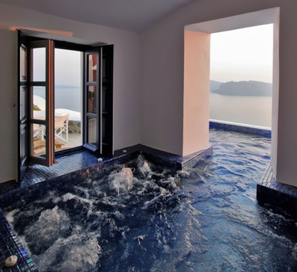 Indoor jacuzzi with dark blue tiles next to open doors overlooking a scenic ocean view, showcasing amazing design ideas. Indoor jacuzzi with dark blue tiles next to open doors overlooking a scenic ocean view, showcasing amazing design ideas.