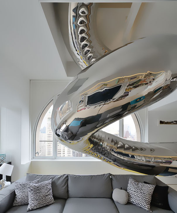 Modern living room with gray sofa and large shiny metallic spiral slide, showcasing amazing design ideas for houses. Modern living room with gray sofa and large shiny metallic spiral slide, showcasing amazing design ideas for houses.