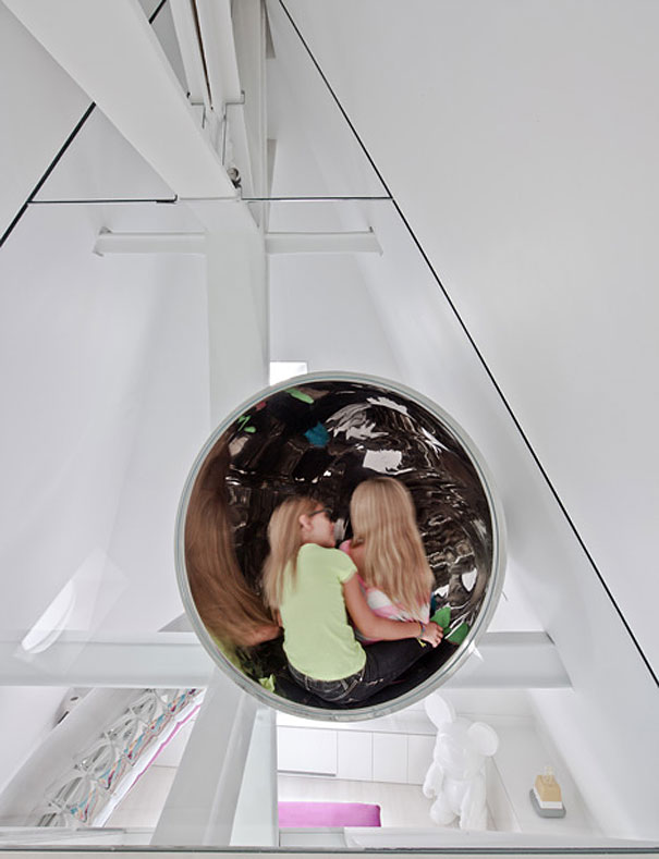 Two children sitting inside a modern reflective indoor slide showcasing amazing design ideas for your house interior. Two children sitting inside a modern reflective indoor slide showcasing amazing design ideas for your house interior.