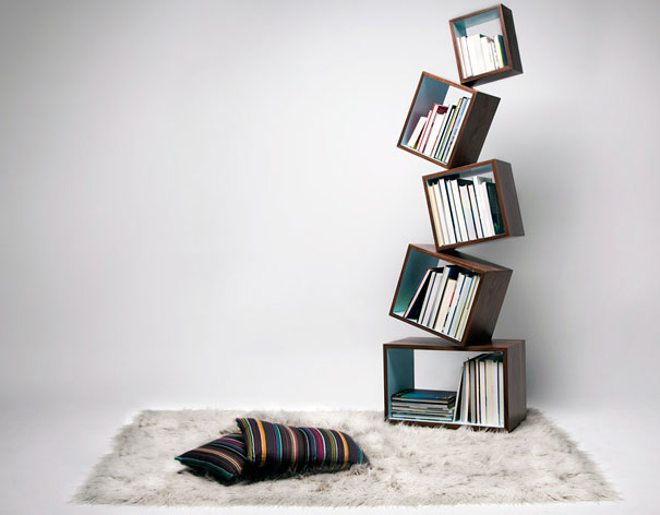 Creative bookshelf design featuring stacked tilted cubes on a fluffy rug with colorful pillows.