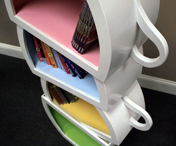 Creative bookshelf design with colorful, cup-shaped shelves stacked vertically. Creative bookshelf design with colorful, cup-shaped shelves stacked vertically.