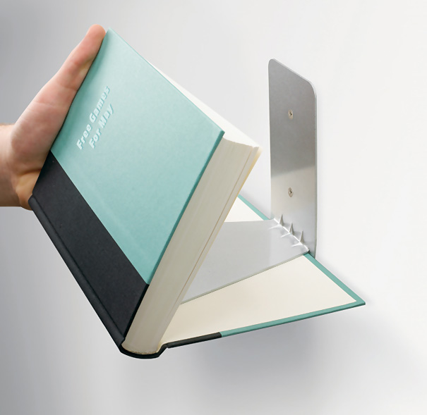 Hand holding a floating bookshelf designed like an open book, attached to a wall.