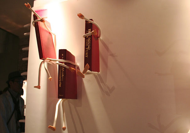 Creative bookshelf design with playful book holders resembling stick figures climbing a wall. Creative bookshelf design with playful book holders resembling stick figures climbing a wall.