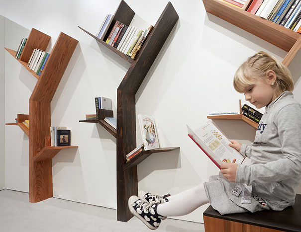 Child reading near creative bookshelf designs shaped like trees. Child reading near creative bookshelf designs shaped like trees.