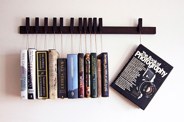 Creative bookshelf design with books hanging on strings against a wall.