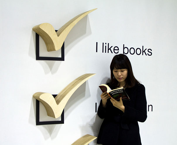Creative bookshelf design featuring large checkmarks with a woman reading a book.
