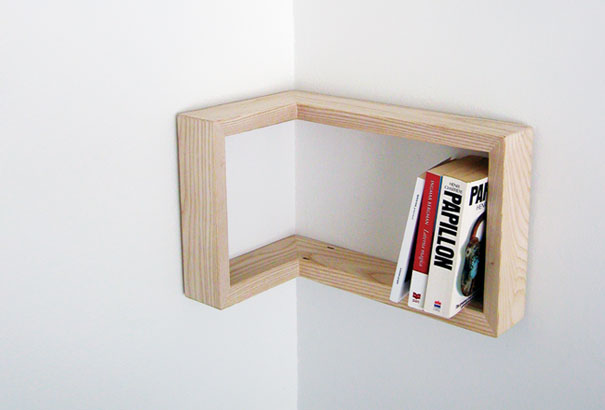 Creative bookshelf design in a corner with a wooden frame holding three books. Creative bookshelf design in a corner with a wooden frame holding three books.
