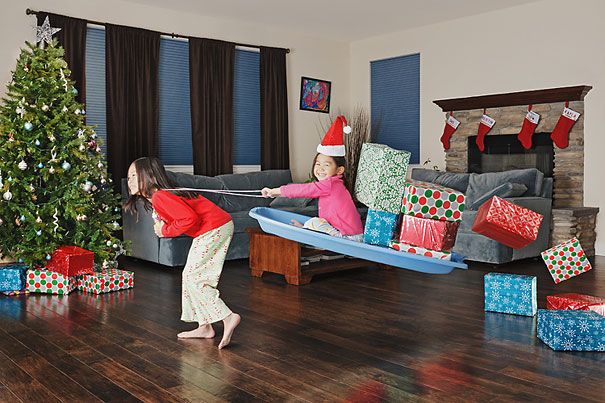 Creative dad captures playful daughters having fun with holiday gifts and decorations in a festive living room setting.