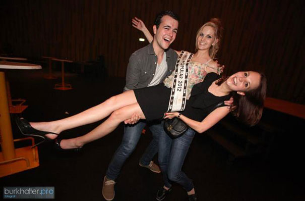 A perfectly timed photo of two people holding a woman sideways, smiling and posing with joy. A perfectly timed photo of two people holding a woman sideways, smiling and posing with joy.