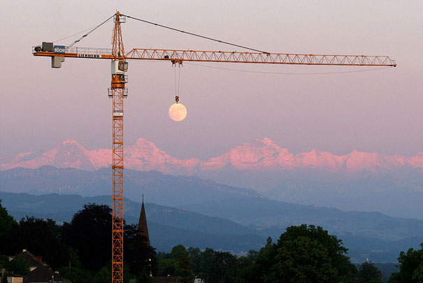 Crane holding the moon against a mountain backdrop, creating a perfectly timed photo illusion. Crane holding the moon against a mountain backdrop, creating a perfectly timed photo illusion.