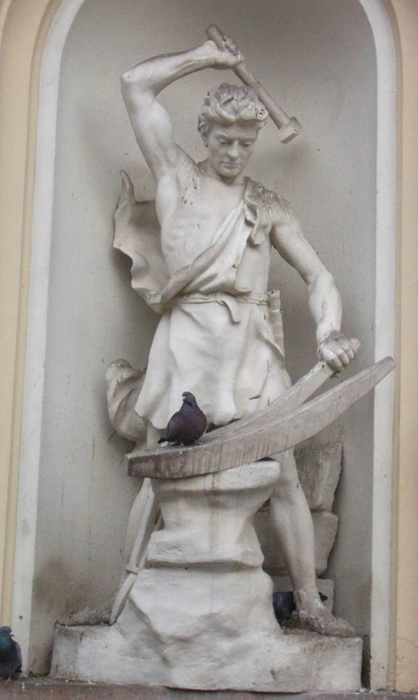 Statue of a man with a hammer above a pigeon perched on an anvil, showcasing perfectly timed photos. Statue of a man with a hammer above a pigeon perched on an anvil, showcasing perfectly timed photos.
