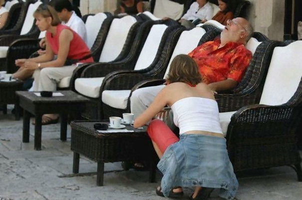 A man in a red shirt appears to have a woman's head as he relaxes in a lounge chair, a perfectly timed photo moment. A man in a red shirt appears to have a woman's head as he relaxes in a lounge chair, a perfectly timed photo moment.