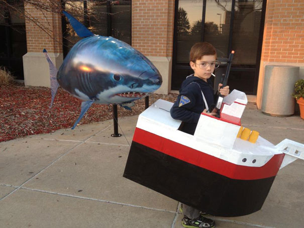 Child in creative Halloween costume as a ship with a shark prop nearby. Child in creative Halloween costume as a ship with a shark prop nearby.