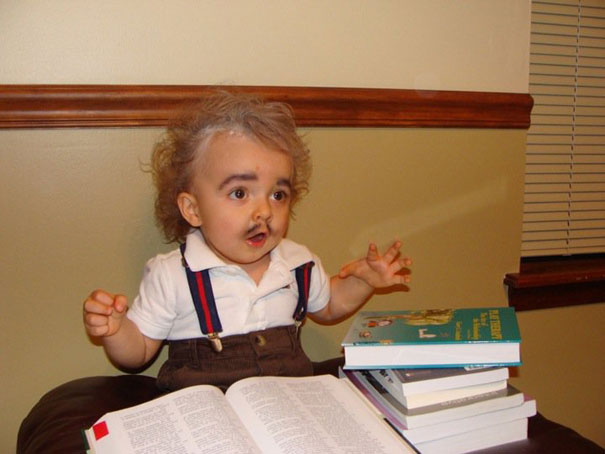 Child in Albert Einstein costume with books, wearing suspenders and mustache, as one of the best kids' Halloween costumes.