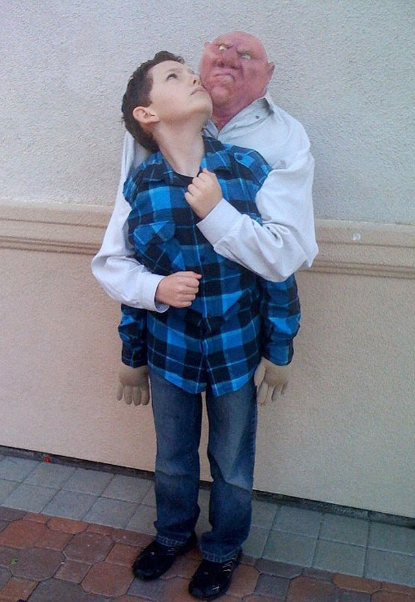 Child in a unique Halloween costume, appearing to be carried by a large comic figure, wearing a blue plaid shirt. Child in a unique Halloween costume, appearing to be carried by a large comic figure, wearing a blue plaid shirt.