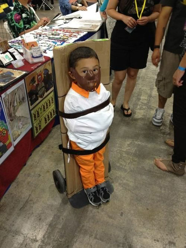 Child in creative Halloween costume, resembling a famous movie character, standing at a convention table.