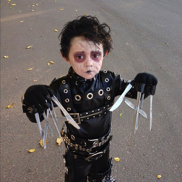 Child in a creative Halloween costume with a black outfit and scissor hands.