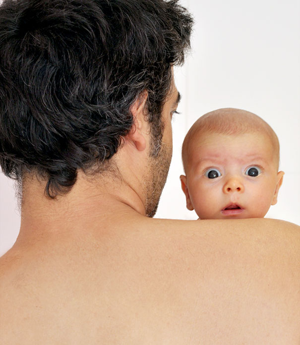 Baby looking surprised over a man's shoulder, highlighting one of the happiest moments with a funny expression.