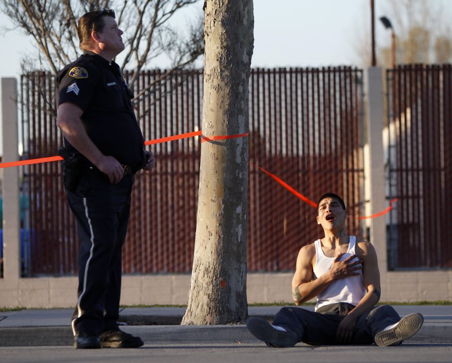 A police officer stands over a distressed man sitting on the ground, capturing a powerful image of human emotion. A police officer stands over a distressed man sitting on the ground, capturing a powerful image of human emotion.