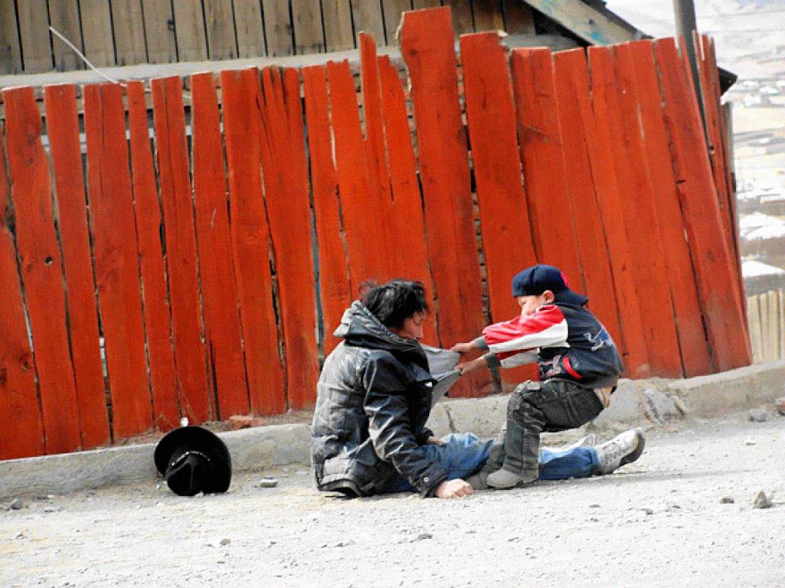 Child helping a man in need on a dusty street, showcasing a powerful moment of compassion. Child helping a man in need on a dusty street, showcasing a powerful moment of compassion.