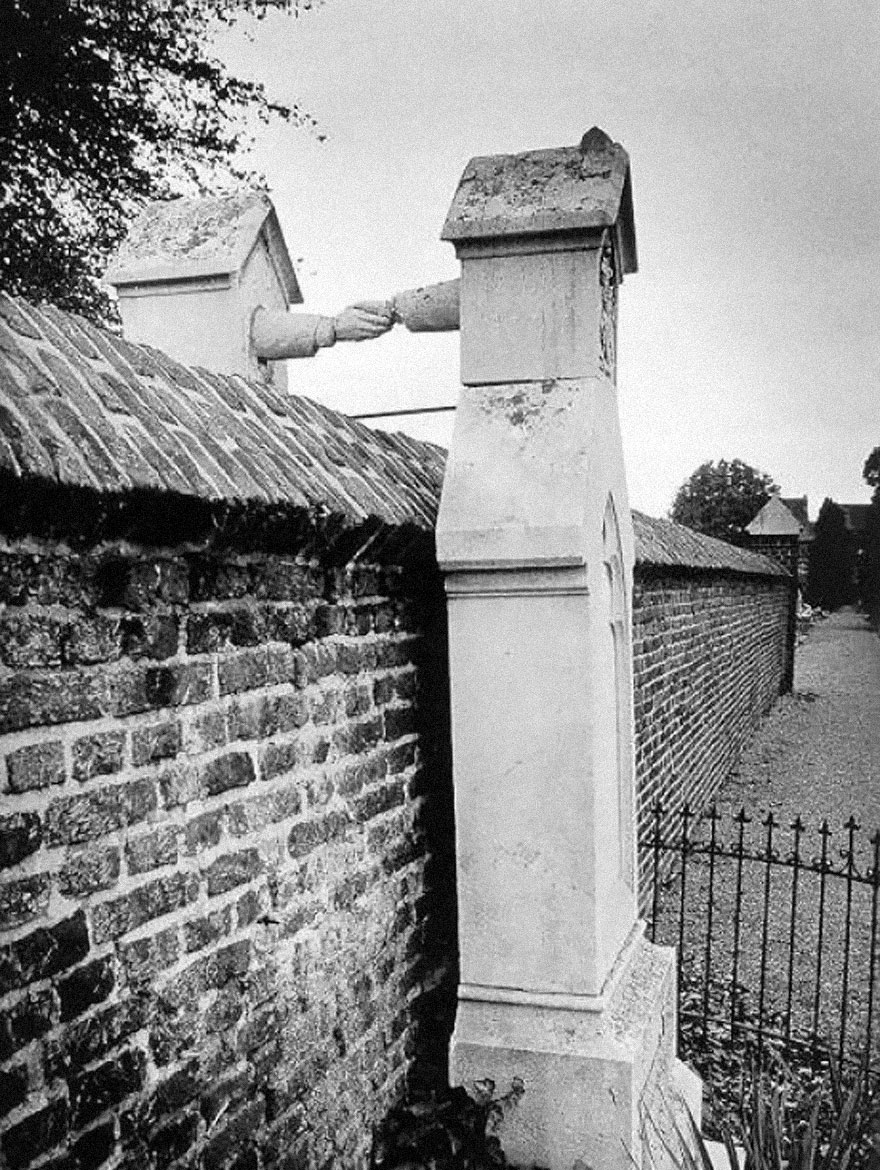 Two gravestones connected by hands over a cemetery wall, symbolizing unity. Two gravestones connected by hands over a cemetery wall, symbolizing unity.