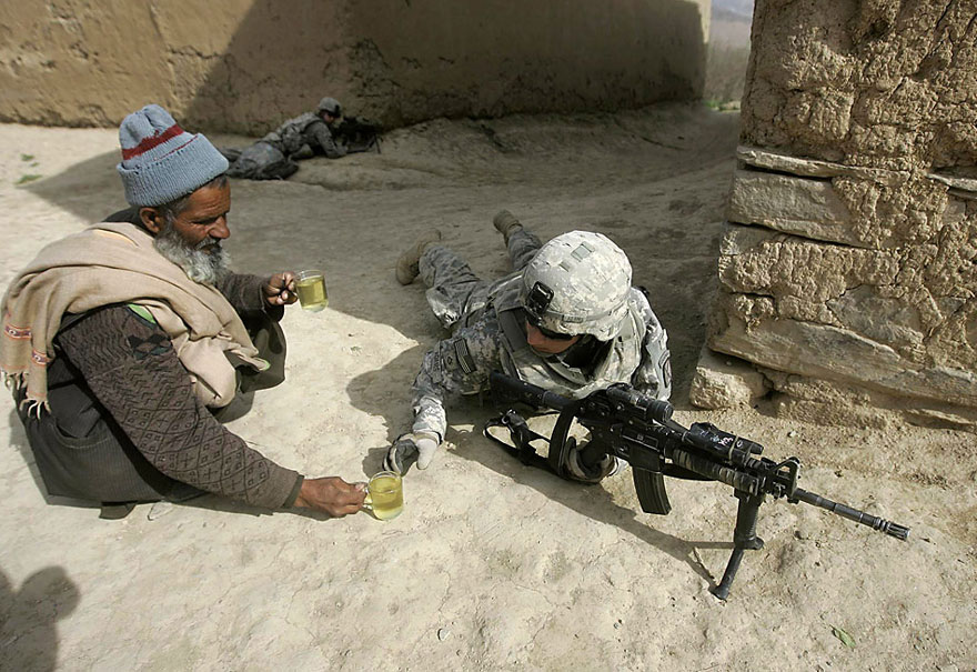 Soldier sharing tea with a local man in a powerful image of humanity amidst conflict. Soldier sharing tea with a local man in a powerful image of humanity amidst conflict.