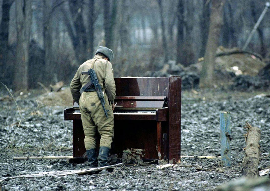 Soldier plays piano in a war-torn forest, illustrating powerful imagery. Soldier plays piano in a war-torn forest, illustrating powerful imagery.