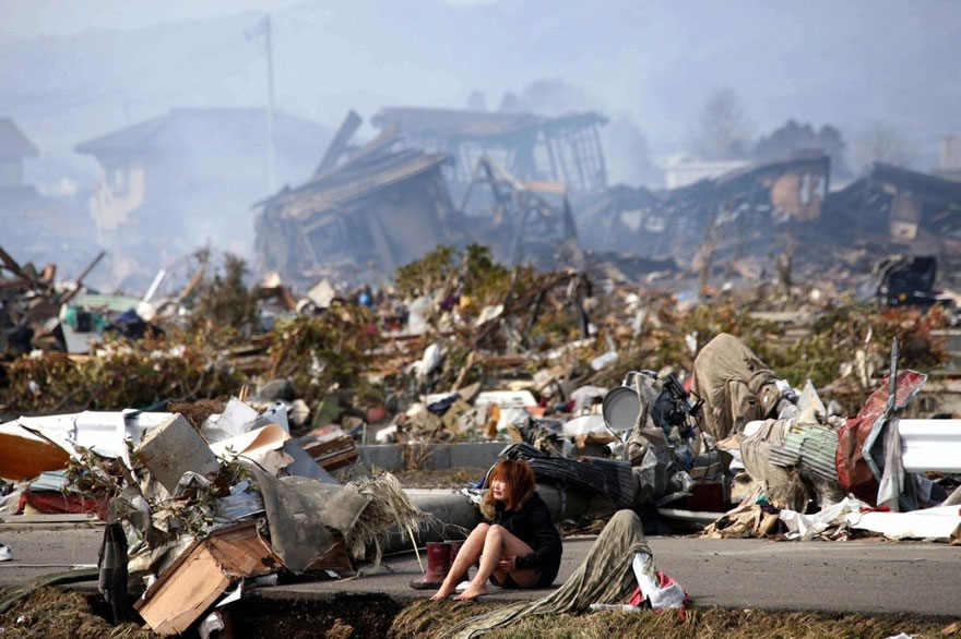Person sitting amidst extensive rubble and destruction, symbolizing powerful images of devastation and resilience. Person sitting amidst extensive rubble and destruction, symbolizing powerful images of devastation and resilience.