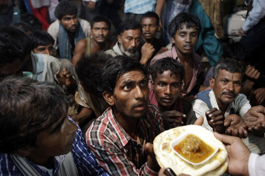 A group of people eagerly reach for food in a powerful image showing desperation and hope. A group of people eagerly reach for food in a powerful image showing desperation and hope.