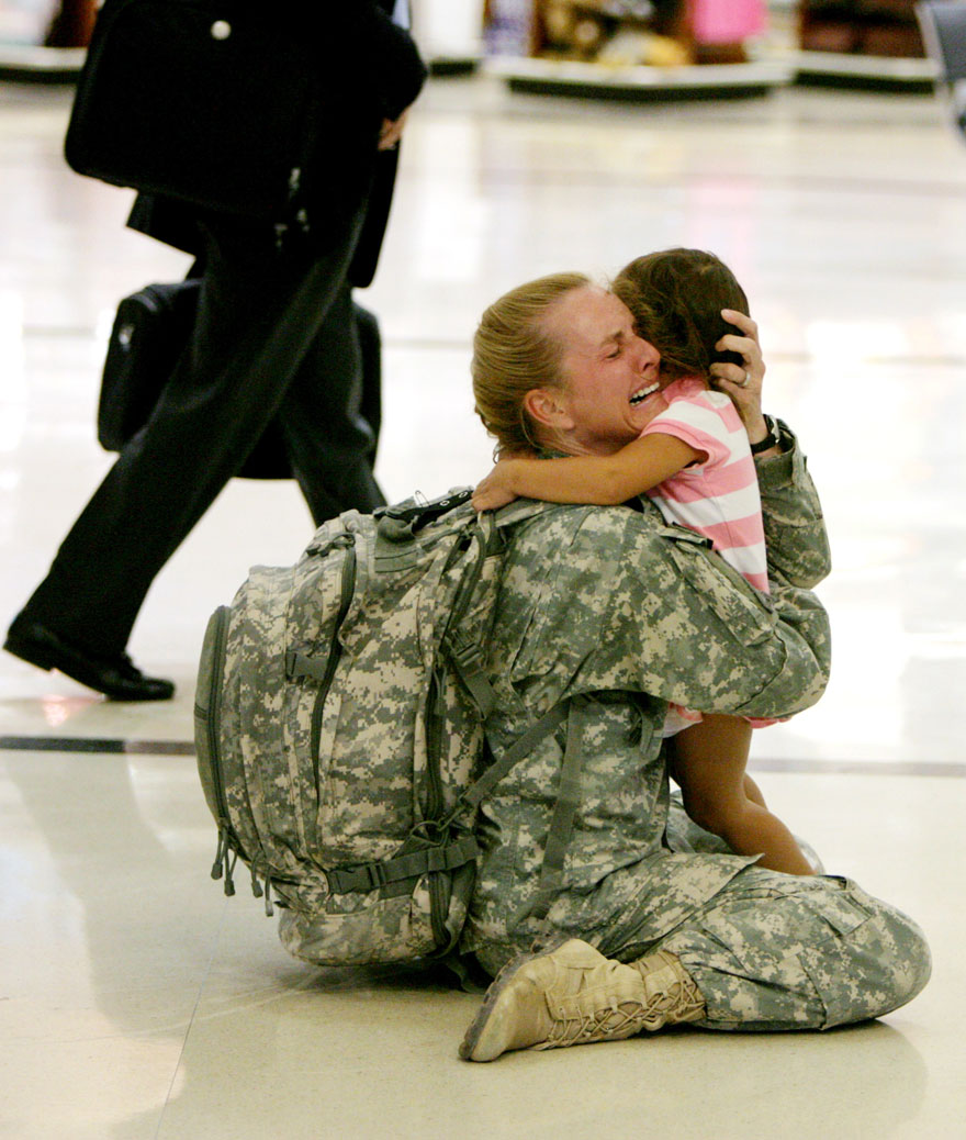 Soldier in uniform emotionally embraces a young child in a heartwarming reunion, capturing a powerful moment in an airport. Soldier in uniform emotionally embraces a young child in a heartwarming reunion, capturing a powerful moment in an airport.